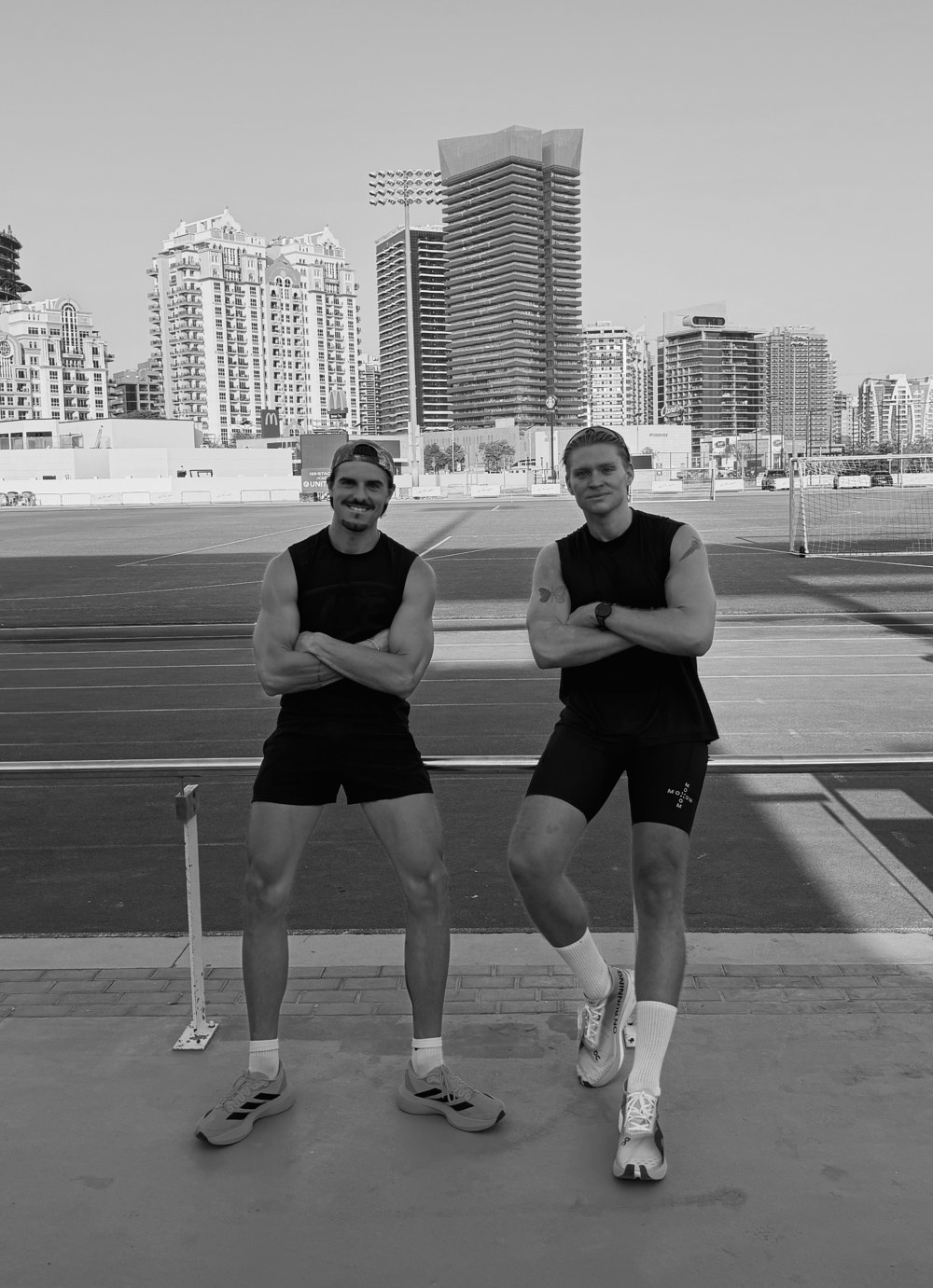 Robbie and a mate standing arms folded by the running track